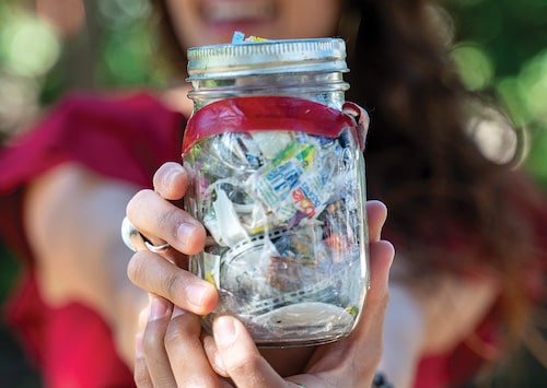 Girl holding a Mason jar filled with 1-year of trash