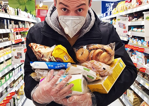 Shopper with a mask and gloves hoarding food in a supermarket.