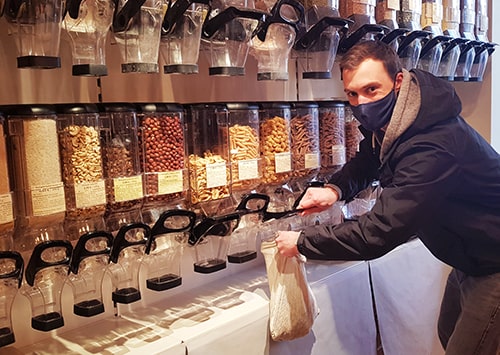 Guy filling up organic pasta in a bulk shop.