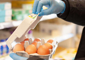 Shopper opening an egg box with plastic gloves.