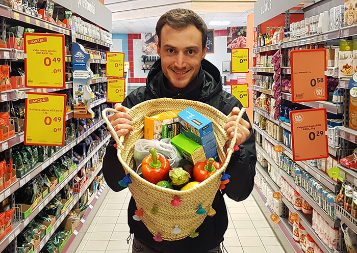 Man carrying a tote bag full of sustainable groceries in a supermarket.