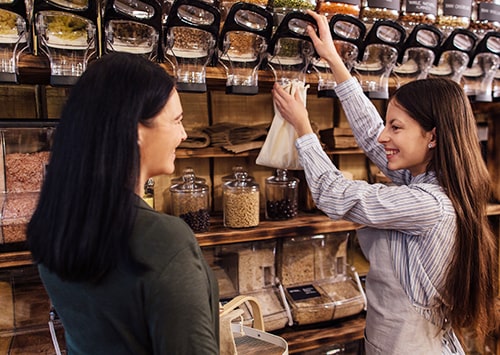 Bulk shop owner filling in food in a jar.