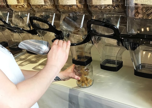 Bulk shop owner fill up a jar with package-free pasta.