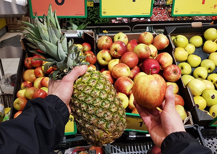 Hands holding a pineapple and a local apple.