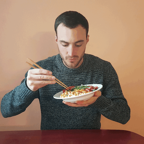 Man eating a vegan poke bowl with chopsticks.