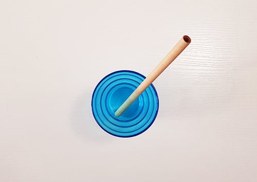 Bamboo straw in a blue cocktail glass.