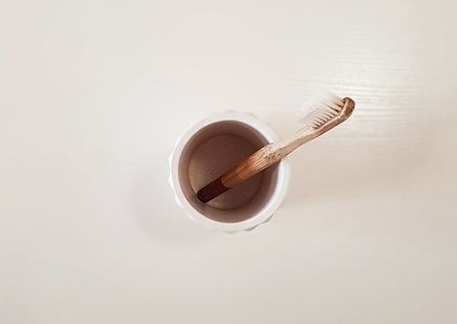 Bamboo toothbrush in a bathroom cup.