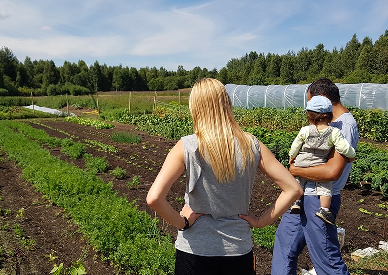 Three people looking at the plants next to the greenhouse.