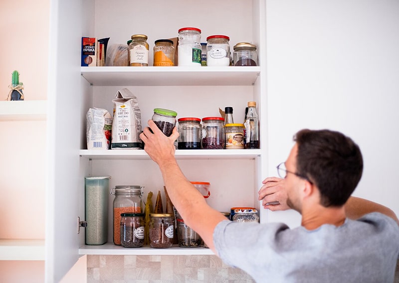 Man reaches for glass jar in pantry