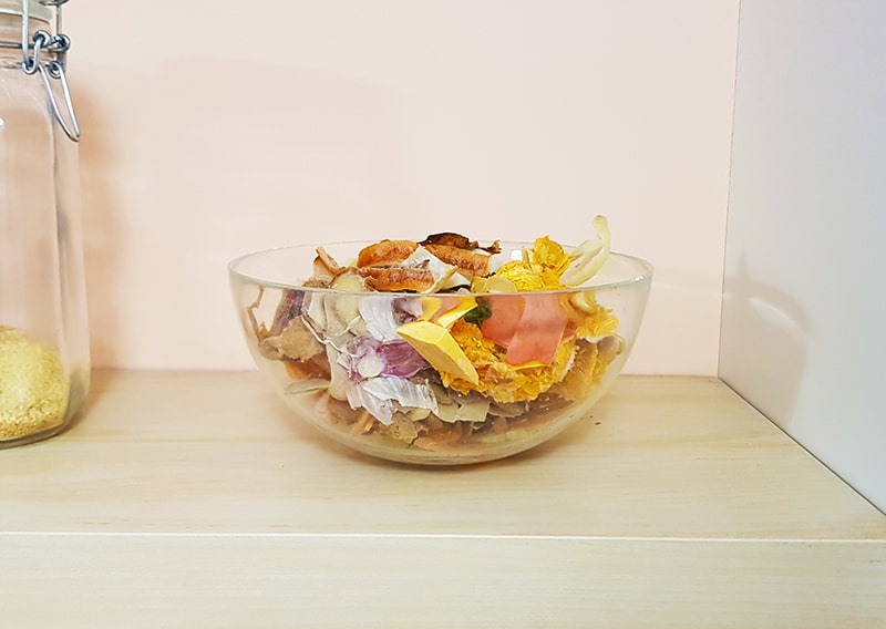 glass bowl with organic food waste on shelf