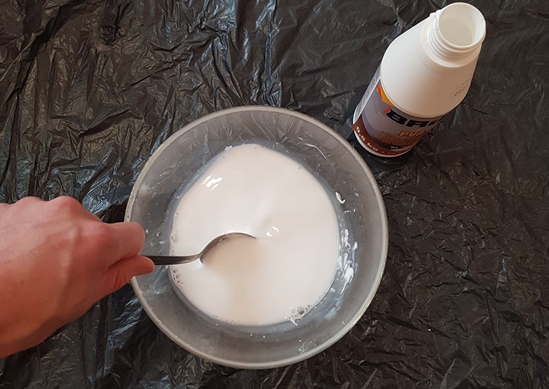 Hand mixing PVA paste and water in a bowl.