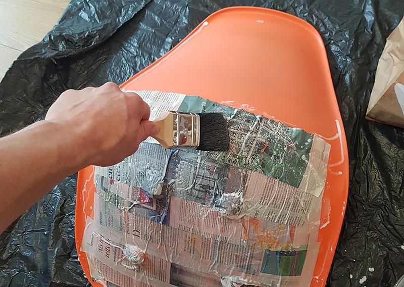 Men brushing the newspaper strip on the chair.