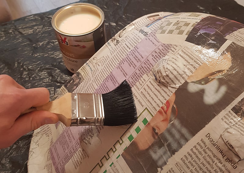 Boy varnishing the chair with a brush.